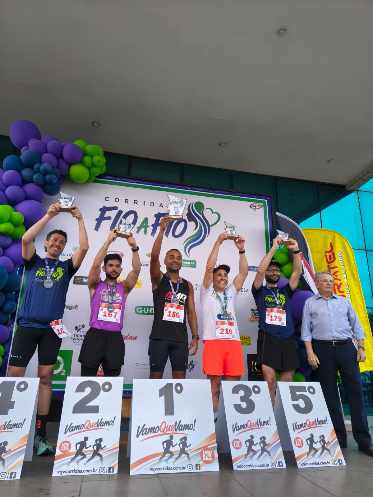 Atletas e treinador em pódio de corrida